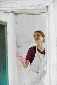 装修中摄影照片_开朗的女画家在白色围裙的家庭装修中