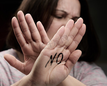 拒绝割韭菜摄影照片_女人向前伸出手掌，做出拒绝提议、保护免受暴力的手势。