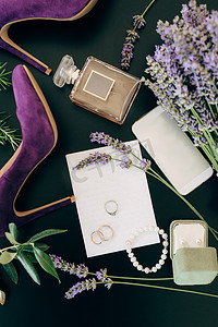 淡紫色高跟鞋、一瓶香水、智能手机、珠宝和绿色背景中的鲜花