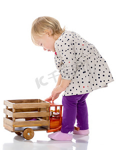 一辆火车摄影照片_小女孩正在玩一辆木制汽车。