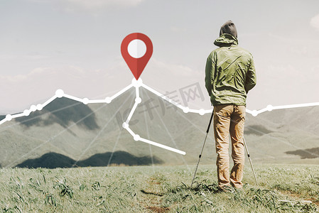 站在山峰上摄影照片_探险家站在路线前面，在山峰上有定位 GPS 引脚。