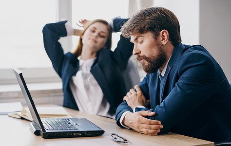 商务男女坐在笔记本电脑情绪办公室前的工作桌旁
