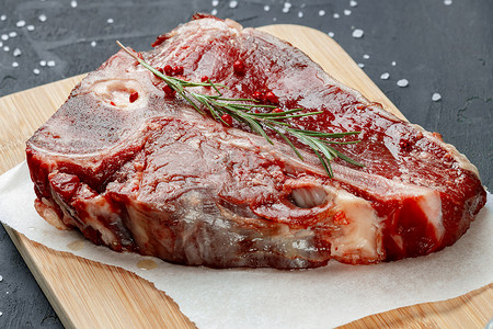 生鲜肉摄影照片_深色背景中带香料的生鲜肉丁骨牛排