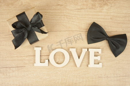 创意父亲节快乐摄影照片_木桌上有蝴蝶领带和礼品盒的木字“LOVE”