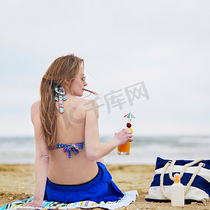 美丽的年轻女子在海滩上放松和晒日光浴