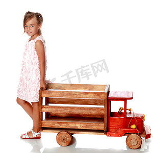 小女孩正在玩一辆木制汽车。