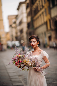 美丽的花朵图案摄影照片_女孩新娘以美丽的花朵图案作为佛罗伦萨的面具，穿着婚纱的时尚新娘戴着面具站在佛罗伦萨老城。