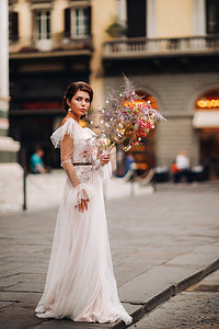 佛罗伦萨的新娘带着美丽的花朵图案作为面具，时尚的新娘穿着婚纱带着面具站在佛罗伦萨的老城区。