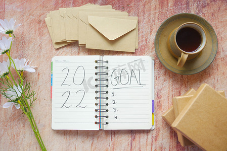 新年规划摄影照片_记事本上的 2022 年新年目标，桌上放着茶和盒子