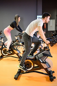 在健身房集体动感单车课上骑现代健身自行车的男子