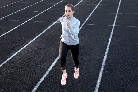 在田径跑道上跑步的跑步运动员在体育场训练她的有氧运动。