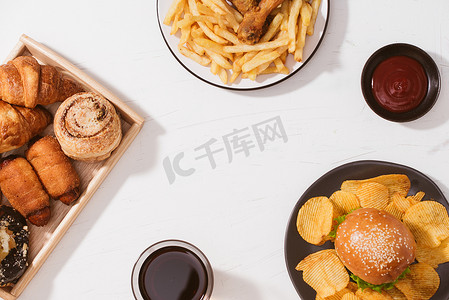 白桌上新鲜出炉的面包、大汉堡、炸脆皮鸡和炸薯条 — 不健康的食物概念