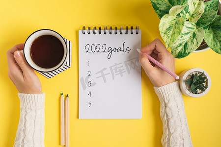 桌面空白记事本和女性手写 2022 年计划和目标文本。