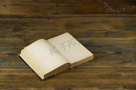 木桌上放着一本打开的旧书，上面有空白页