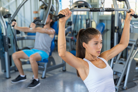 健身女孩在拉特下拉机上锻炼肩膀和上背部，在健身房进行力量训练
