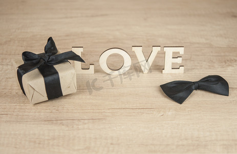 木桌上带蝴蝶领带和礼盒的木字LOVE
