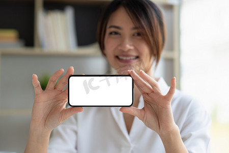 微笑标语摄影照片_微笑美丽的亚洲女商人展示空白智能手机显示器，带有标语或短信的复制空间区域。