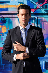 打领带的男人摄影照片_城市背景中穿蓝色西装打领带的年轻商人