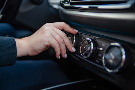 控制控制系统摄影照片_一位女士的手转动旋钮来调节现代高档汽车的气候控制系统。