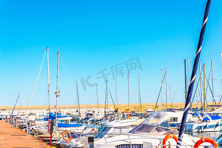 豪华游艇摄影照片_美丽的豪华游艇和机动船停泊在港口、炎热的夏日和码头的蓝水、蓝天