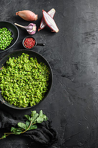 糊状豌豆无麸质煮熟的煎锅和碗中的豌豆，配以薄荷葱胡椒和盐 s 黑石表面有机酮食品顶视图空间文本垂直概念
