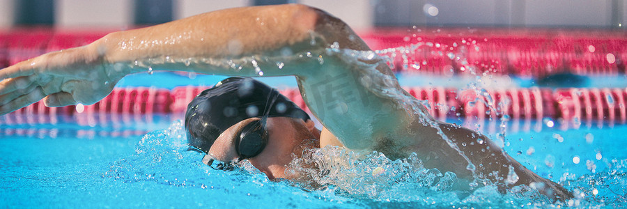 游泳比赛摄影照片_运动和健身概念运动运动员在泳池训练有氧运动中游泳，进行自由泳爬行技术进行速度比赛。