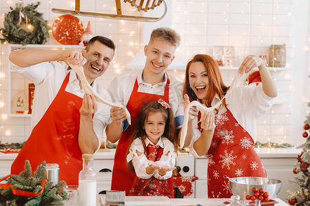 圣诞一家人摄影照片_圣诞节前，一家人站在厨房里，手里拿着面团