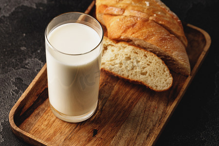 木板上的一杯牛奶和切片长棍面包