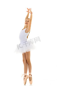 芭蕾摄影照片_穿着芭蕾舞短裙和足尖鞋的可爱小女孩在白色背景的工作室里跳舞。