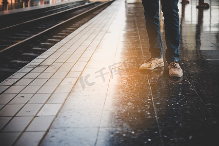 一个穿牛仔裤的年轻人的脚正在等火车 a