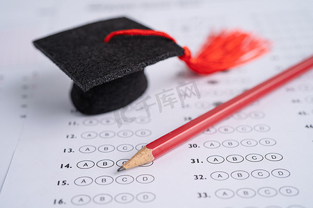 答卷摄影照片_答卷背景上的毕业差距帽子和铅笔，教育学习测试学习教学理念。