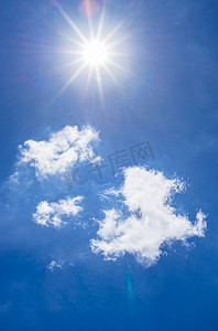 蓝色白云摄影照片_深蓝色的天空上明亮闪亮的阳光与蓬松的白云