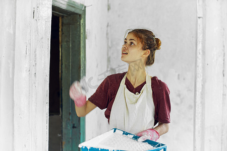 开朗的女画家在白色围裙的家庭装修中