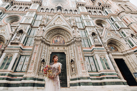 佛罗伦萨的新娘带着美丽的花朵图案作为面具，时尚的新娘穿着婚纱带着面具站在佛罗伦萨的老城区。