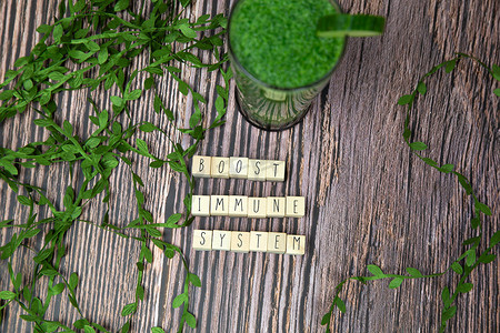 增强您的免疫系统 — 木质背景纹理上的鼓舞人心的文字，配以一杯新鲜的绿色、蔬菜汁、健康的生活方式和幸福概念
