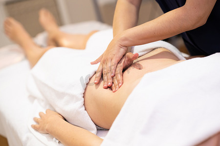 理疗摄影照片_在理疗中心接受腹部按摩的女士。