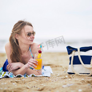 晒水摄影照片_美丽的年轻女子在海滩上放松和晒日光浴