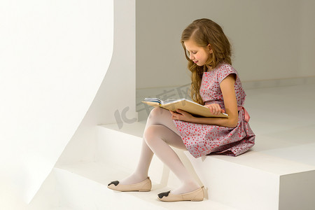 美丽的金发女孩坐在台阶上和 Int 一起看书