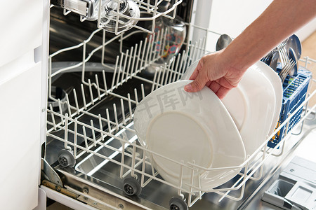 家庭主妇摄影照片_从洗碗机中取出盘子的女人