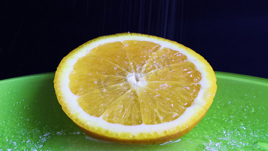 切片水果摄影照片_一片圆圆的橙子，看起来多汁，撒上糖后开胃。