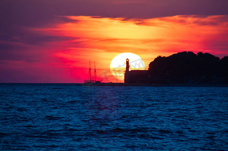 与灯塔和帆船的史诗般的日落景观