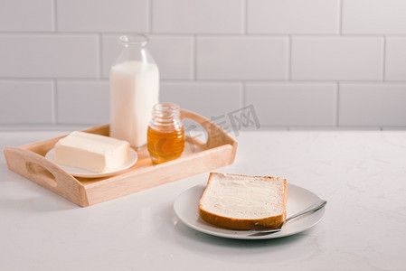 早餐桌，配有面包片、黄油、牛奶和蜂蜜