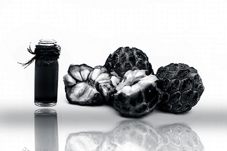 未加工的有机新鲜水果番荔枝、糖苹果或甜番莲，其油装在透明玻璃瓶中，与白色及其反射隔离。