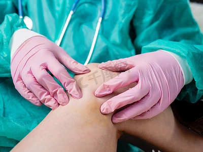 一名戴着医用手套的外伤科医生在对患者进行例行检查时触诊受伤的膝盖。