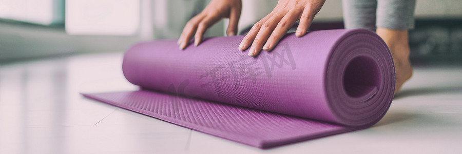 在家瑜伽的女人在客厅里滚动粉色运动垫开始热身冥想禅宗健康横幅全景公寓客厅生活方式