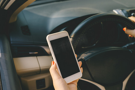 年轻的女司机在车里使用触摸屏智能手机和 gps 导航。
