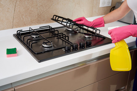 打扫卫生的摄影照片_用厨房用具、家居概念或卫生和清洁清洁燃气灶。