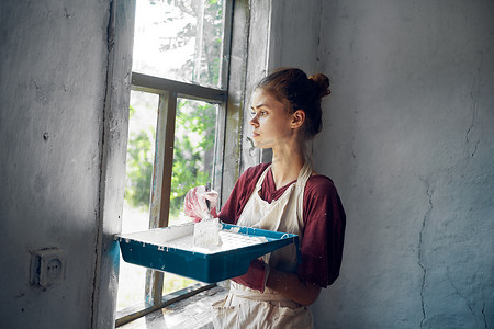 女人在房子内部房间装修中油漆窗户