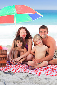 家人在海滩上的太阳伞下野餐