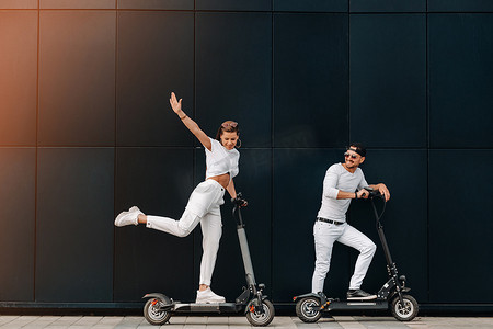 一个女孩和一个男孩骑着电动滑板车在城市里行走，一对骑着滑板车相爱的情侣。